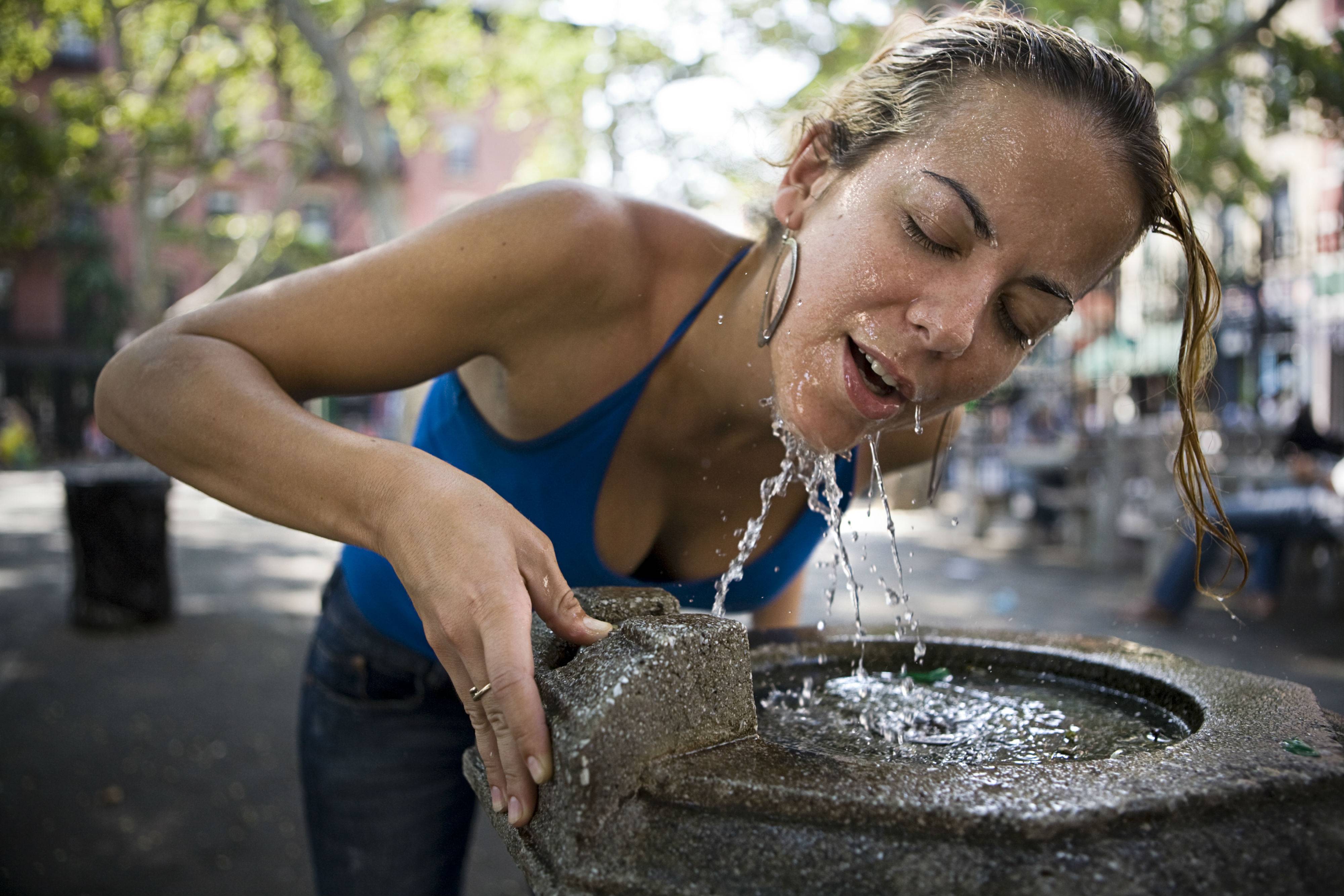 Хочу холодную воду. Девушка обливает себя водой. Пить воду в жару. Жажда воды. Девушка пьет воду жара.